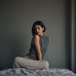 a woman sits on top of a bed with her arms crossed