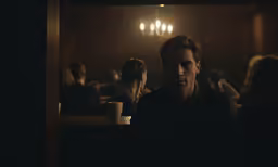 there is a man sitting at the counter in the dark