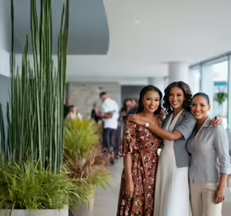 two women standing side by side in front of a plant