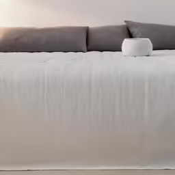 a white vase sitting on top of a bed in a room