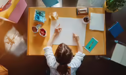 a woman is sitting at a table with a large piece of paper