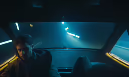 a man sits in the front seat of a car with his head up