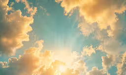 a sky full of bright clouds with the sun peeking out