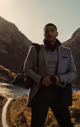 a black man standing in the mountains with a black camera