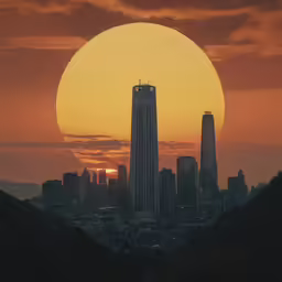 the sun setting behind a city skyline with skyscrapers