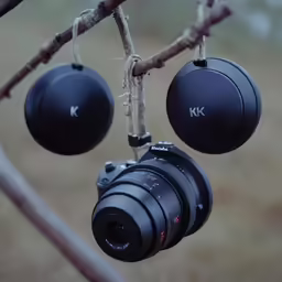 some type of camera hanging on a branch