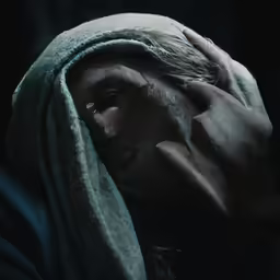 a person covered in a blanket with their hands in their face