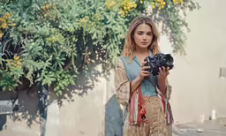 young woman taking pictures with a camera in a courtyard