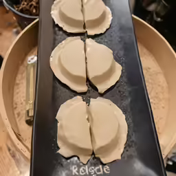 three ravioli on a pan next to spoon and food