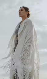 a woman is wearing an all - white shawl and matching sandals