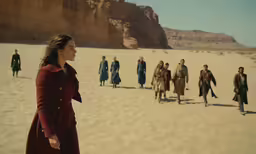 a woman is standing with other men in the desert