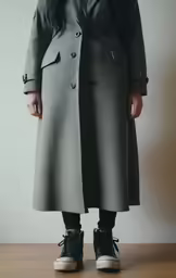 a woman in black sneakers wearing a gray coat