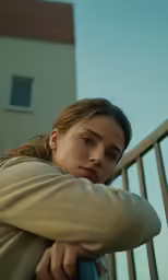 a young girl leaning on her railing with her hand under her right arm