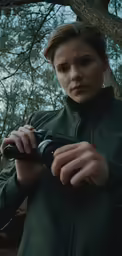 a woman is holding a camera outside under some trees