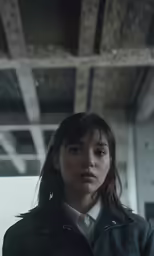 a woman looks over her shoulder, with an unfinished ceiling above her