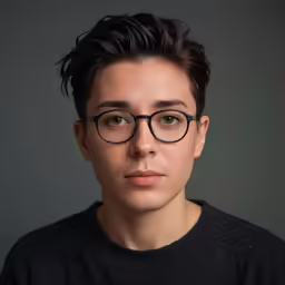 a man with a black sweater and glasses looks forward