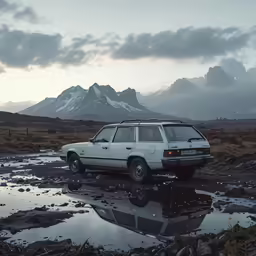 an old automobile is in a muddy field with a mountain in the background
