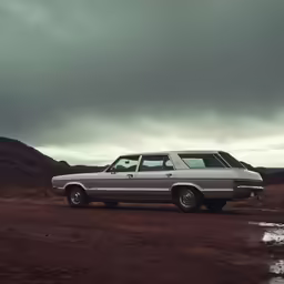 a dirty, off - road car sits in front of some mountains
