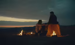 two people stand near the fire pit with their arms wrapped around one