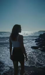 a woman standing in the water at the beach