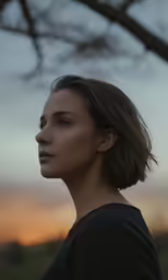 a woman in black shirt standing next to a tree