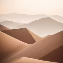 a desert landscape with sand dunes and hills in the background