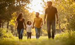 family with child on walking through park at sunset