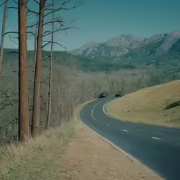 two cars drive down the curvy curved road near mountains
