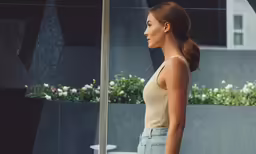 a young woman standing next to a lamp post in the daytime