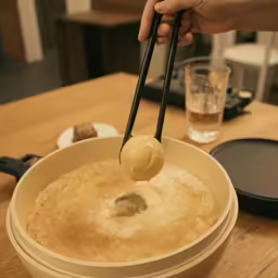 a person pouring something into a bowl and dipping it into a fork