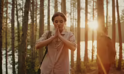 two people praying in front of the trees and sun
