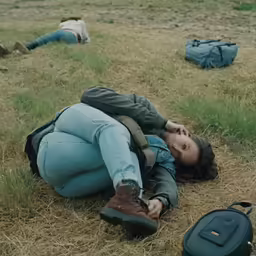 a girl in jeans and brown boots is laying on the ground