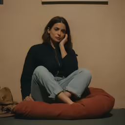 a woman sits with her head propped on her hand