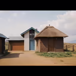 two huts on an arid desert with grass and dirt, one has blue doors
