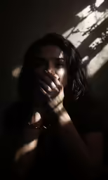 a woman covering her mouth and holding her hands