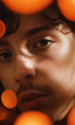 a man that has long hair and he is surrounded by orange balls