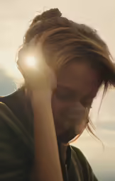 woman with a messy ponytail looking at the sky