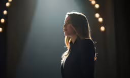 a woman in black is standing at a stage