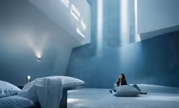 a woman sitting on top of a cushion next to a bed