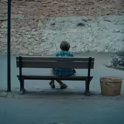 there is a woman sitting on a bench next to a bucket