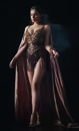 the woman is posing wearing a gold costume and she has a pink shawl over her shoulders