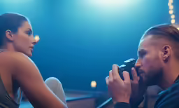 a man with a camera taking a picture of another woman on stage