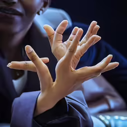 woman in a suit with her hands up with both hands out