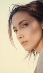 a beautiful woman with brown hair and earrings looking into the camera