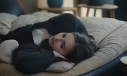 a woman laying down on top of a black couch
