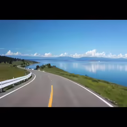 a highway going along side the sea towards mountains