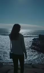 a woman is looking out over the ocean