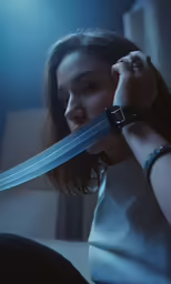 a woman holding up a blue object with a long curved blade