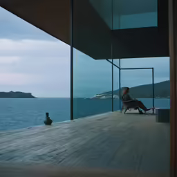 the woman sits on the deck watching the ocean