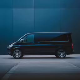 a black van parked against a wall in an empty parking lot